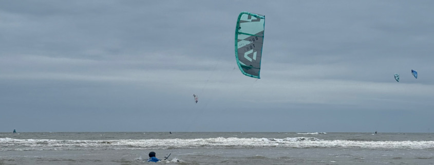 Vrouw bodydragt door de zee tijdens de les kitesurfen bij Surfschool Castricum.