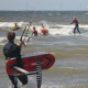 Man loopt met foil het water in tussen de surfers bij Surfschool Castricum. Voorrangs Regels Kitesurfen.